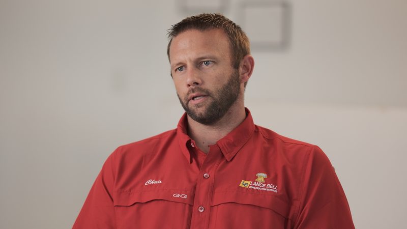A member of the Bell team in a red company shirt, photographed indoors against a plain wall.