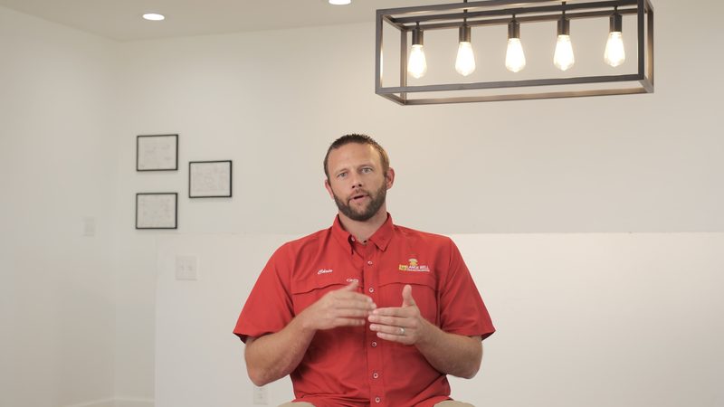 A member of the Bell team in a red company shirt, seated indoors with his hands together as he speaks.