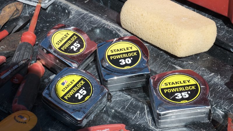 Tape measures, screwdrivers and other hand tools laid out on the tailgate of a work truck